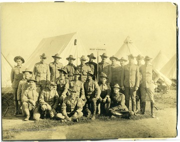 "Sergeant Clinton T. Manear 2nd from left kneeling with hand on knee."