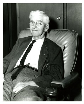 An unidentified male with earphone sits in a couch.