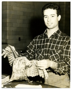 An unidentified male holds a bird specimen.