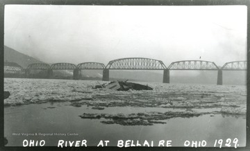 A view of the Ohio River at Bellaire; in the midst of ice covered river a boat  partially under the water is visible.