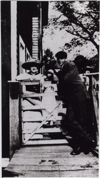 A man and a woman are posed at the gate which helped keep animals out of the Webster Springs Hotel bottom.