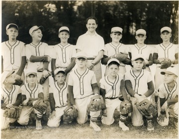 Team portrait of a little league baseball team coached by George DeAntonis (standing, middle back row).