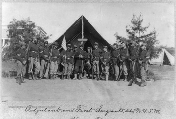 A group portrait of an adjutant of the regiment, front and center, with a young drummer boy on his left and flanked by several first sergeants during the Civil War. None of the subjects are identified.