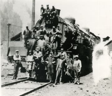 Unidentified railroad workers pose on a locomotive.