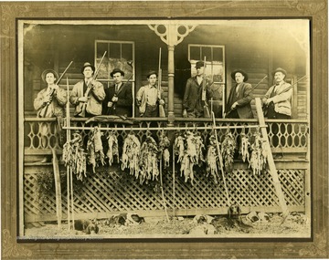 Left to right: Wild Balland, Geo Meadows, Ed Cunsh, Bill Cunsh, Mr. Balleneng, J. L. Keatley and John Cunsh. Shows the men with several hunting dogs and their hunted rabbits. 