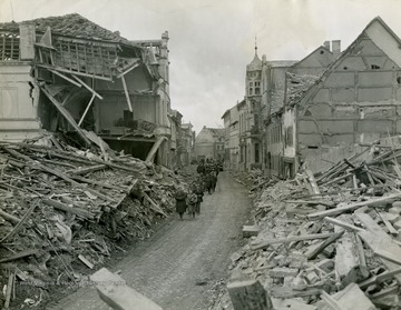 Information on back of photo reads: "German civilians march through newly captured Zulpich, Germany, to receive instructions on their conduct from military government unit with 9th Infantry Division of 1st U.S. Army. Town was hard hit by U.S. bombers blasting path to Rhine."