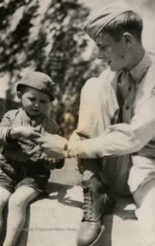 Information on back of the photo reads: "Puzzled but curious, a little Russian boy accepts a stick of chewing gum from his new friend, a U.S. Air Forces solider at the Russian terminus of Italy-Russia shuttle missions flown by heavy bombers of the U.S. Fifteenth Army Air Force. Since June, 1944, Allied bombers from England and Italy, escorted by fighters, have flown to bases in Russia, and return, attacking enemy targets in occupied Europe en route."