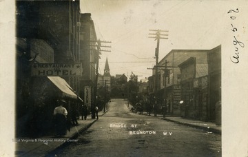 Shops line the street and a horse and buggy can be seen up the road. See original for correspondence. (From postcard collection legacy system.)