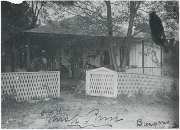 People sit on the porch of the fenced off building. No subjects identified. 