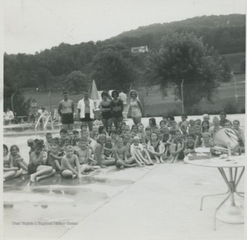 Swimming students and teachers gather for a group photo beside the pool