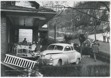 A group of men inspect the damage caused by the collapse of one of the home's brick support columns. Two police officers seen in the background. Subjects unidentified. 