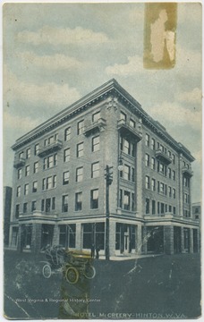 Drawing depicts a group riding past the hotel building in an old-fashioned automobile.