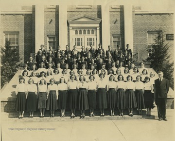 The group poses on the steps of the building. In the back row on the far left, Charles Lago is pictured. Other subjects unidentified. 