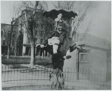 Timberlake is sitting in one of the fountain bowls. The leafless trees in the background suggest it is wintertime, which is likely why the fountain is not running. 