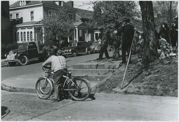 Two young boys on bicycles watch Moorman Parker perform the re-enactment on a horse in front of the First Methodist Church building located on the corner of Ballengee Street and Third Avenue. 