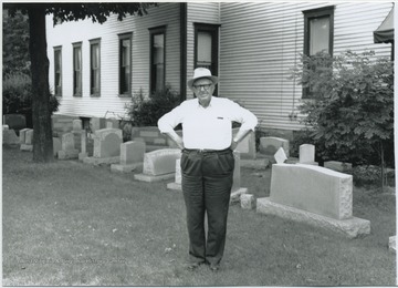 The former sheriff pictured beside his home. Behind him are blank tombstones. 