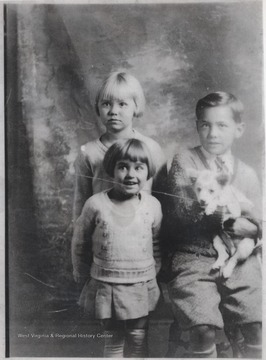 The girls stand next to their brother holding the family pup.