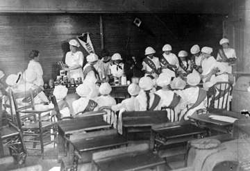 Group of girls watch the teacher demonstrating the process.