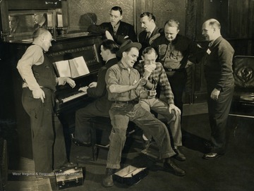 Two of the mill men share coffee, still in their work clothes, after receiving a call to come from the mill to the main office for rehearsal right away. They were preparing to go to Chicago for a war bond program. See original photograph for further description.