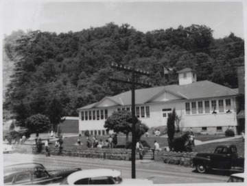 School children scatter the lawn in front of the building.