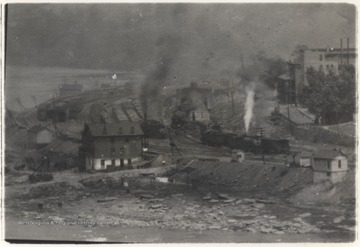 Steam shoots from a locomotive passing through the city.