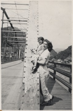 Garten holds up the Smith girl to rest her on the beams of the old bridge.