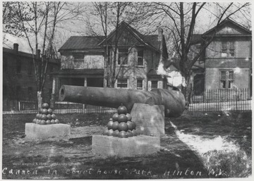 Pyramids of cannon balls sit on either side of the rustic cannon. 