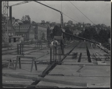 Two unidentified men observe what has been done to advance the construction of the building. 