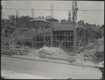 Building materials line the sidewalk beside the half-way constructed building. 