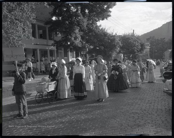 Parade participants dressed in old fashioned clothing assemble in the street. A man holds a sign reading, "Employees." Subjects unidentified.