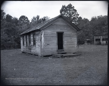 An American flag hangs from the small schoolhouse. 