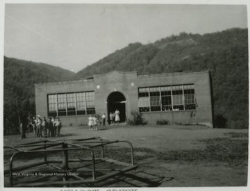 School children loiter on the school grounds in front of the building. Subjects unidentified. 