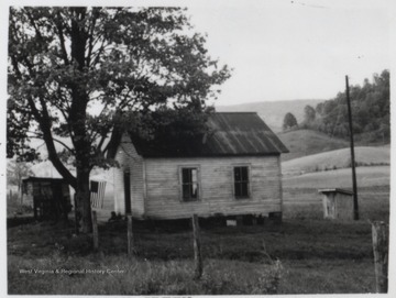 An American flag hangs from the small schoolhouse. 