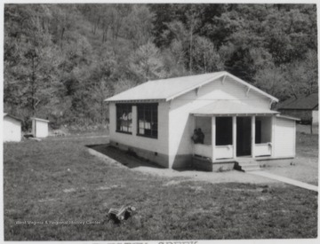 Two unidentified school children are pictured sitting on the schoolhouse porch. 