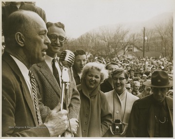 Roy Williams speaks to a crowd in front of the East Bank High School building after the East Bank High School basketball team won its first ever state championship title.Jerry West led the East Bank High School basketball team to victory as its starting small forward. He was named All-State from 1953–56, then All-American in 1956 when he was West Virginia Player of the Year, becoming the state's first high-school player to score more than 900 points in a season.