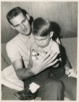 Jerry West sits with his son after he broke his thumb while playing with the Lakers.  West's broken thumb prevented him from playing several games that year.