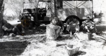 Edward C. Tabler and other individuals resting and eating lunch along the Impakwe River, Africa.  