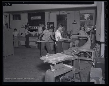 A group of young, male campers work with wood and tools in their shop class. 