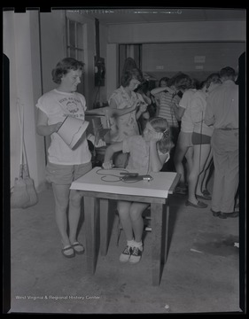 Female campers work together to assemble lamps.