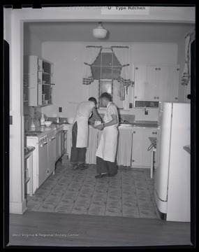 Two unidentified boys work together in the kitchen.