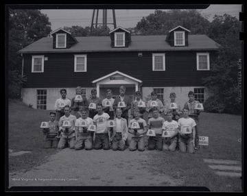 A group of boys pose with their finished crafts after a class in lamp-making. 