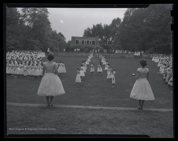 Two girls carry flags down the field during the ceremony. Subjects unidentified. 