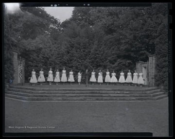 A group stands on an outdoor stage in preparation for the ceremony. 