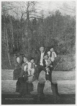 Man, woman, and child identified as Page family sitting on a log.