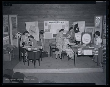 Instructors demonstrate how to properly sew with Singer sewing machines. Subjects unidentified. 