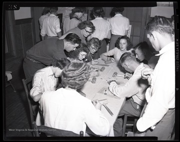 A group of boys and girls learn to work with leather. Subjects unidentified. 