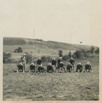 Coach Fred Carrol, left, watches as his football players run a play.