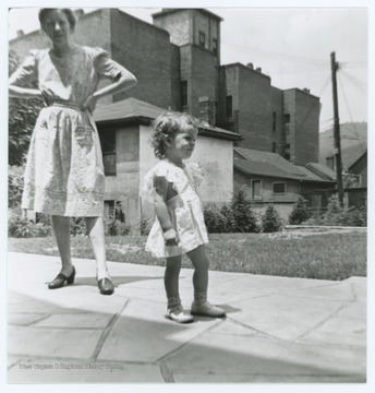 Inscription on reverse indicates area is the alley between 3rd & 4th Ave behind the Hinton Hospital.  Pictured is a woman and child, one of whom is identified as "Miller's Mother".