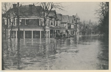 Photo postcard of unidentified homes during a 1913 flood.  Two boats are visible floating on the flooded streets.  Postcard is part of a souvenir book of 1913 flood images.