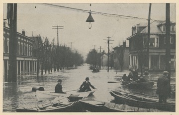 Photo postcard of several boats floating in an intersection in Wheeling, W. Va. during a 1913 flood.  Postcard is part of a souvenir book of 1913 flood images.